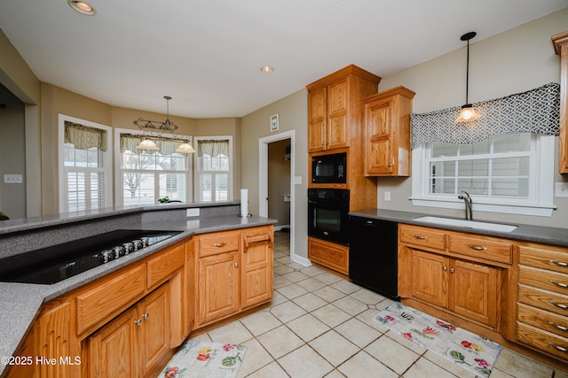 kitchen with brown cabinetry, dark countertops, a sink, and black appliances