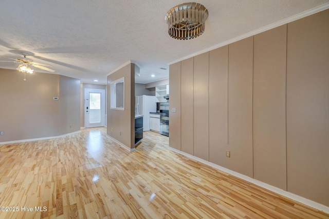 unfurnished living room with crown molding, baseboards, light wood-type flooring, a textured ceiling, and a ceiling fan