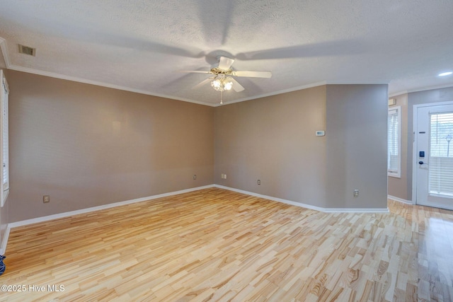 empty room featuring visible vents, a textured ceiling, light wood-style flooring, and crown molding