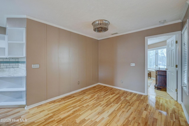 spare room with crown molding, baseboards, light wood-type flooring, and a textured ceiling