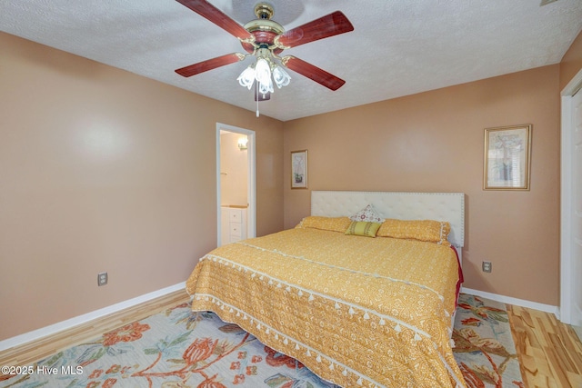 bedroom featuring ceiling fan, baseboards, a textured ceiling, and wood finished floors