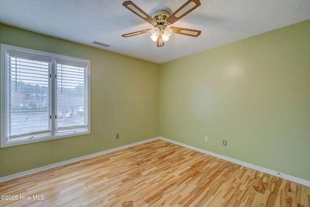 unfurnished room featuring visible vents, baseboards, a textured ceiling, and wood finished floors