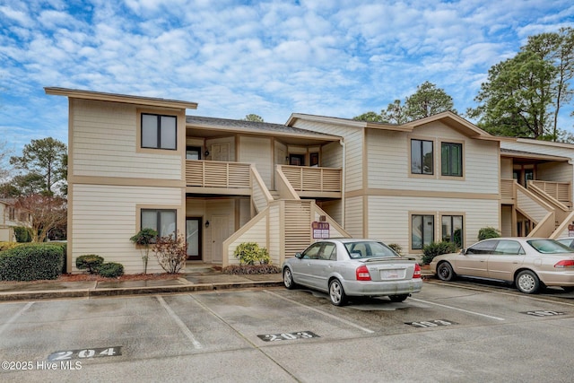 view of building exterior featuring stairway and uncovered parking