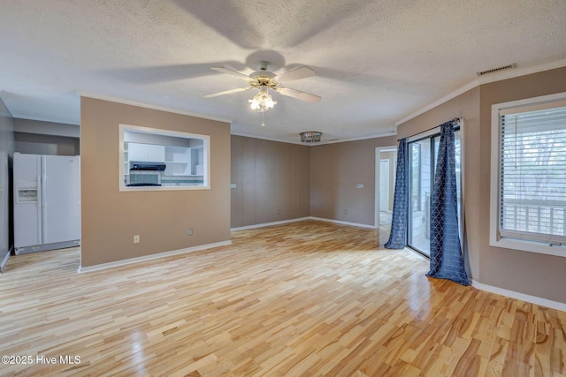 empty room with visible vents, a textured ceiling, light wood-style flooring, and ornamental molding