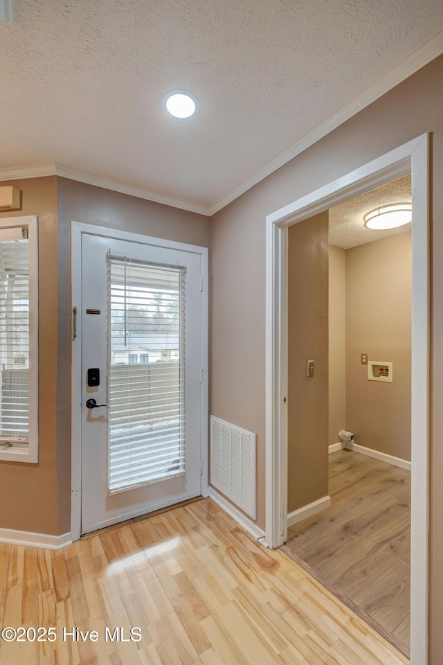 doorway featuring wood finished floors, baseboards, visible vents, a textured ceiling, and crown molding