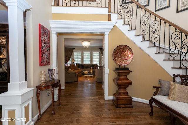 foyer with a towering ceiling, baseboards, stairs, dark wood finished floors, and decorative columns