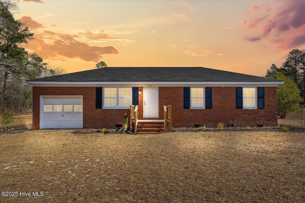 single story home featuring a garage, brick siding, and crawl space