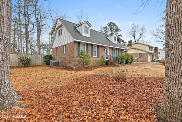 cape cod-style house with central AC, brick siding, a shingled roof, fence, and crawl space