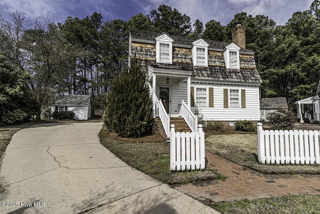 view of front of home featuring crawl space, a fenced front yard, a chimney, and an outbuilding