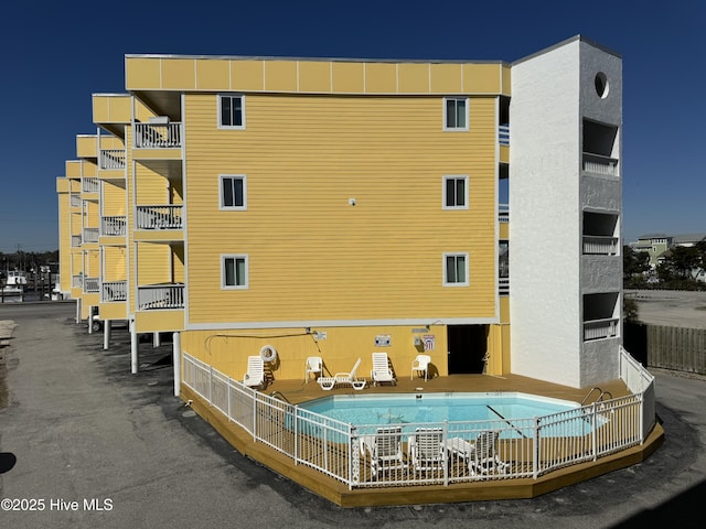 view of building exterior featuring fence and a community pool