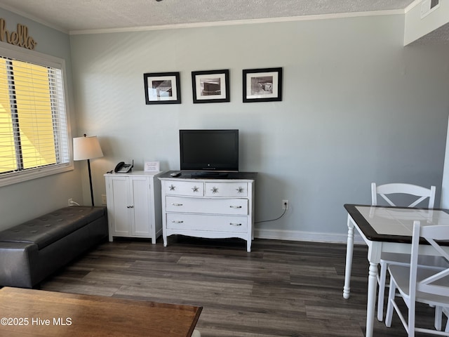 sitting room featuring a textured ceiling, dark wood-type flooring, visible vents, baseboards, and ornamental molding