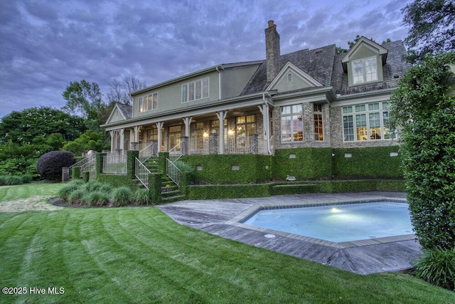 back of property with a yard, a chimney, and stucco siding