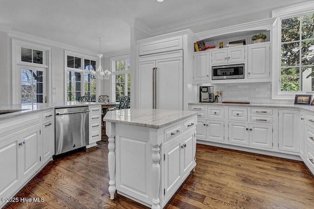 kitchen with built in appliances, white cabinetry, ornamental molding, dark wood finished floors, and decorative light fixtures