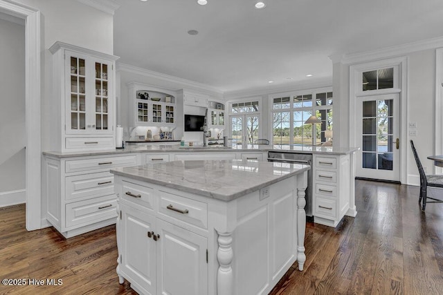 kitchen with a kitchen island, glass insert cabinets, a peninsula, crown molding, and white cabinetry