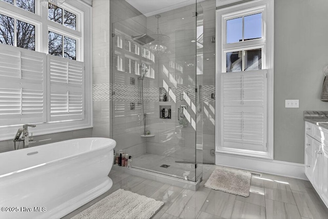 full bath featuring a soaking tub, vanity, baseboards, and a stall shower