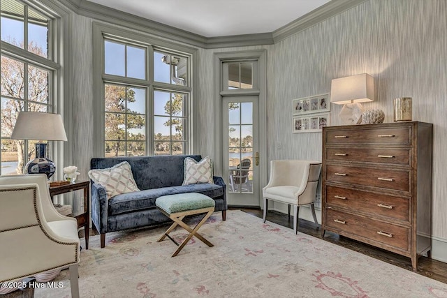 living area with ornamental molding, wallpapered walls, and wood finished floors