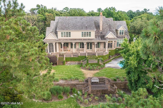 back of property featuring a yard, a chimney, and a vegetable garden