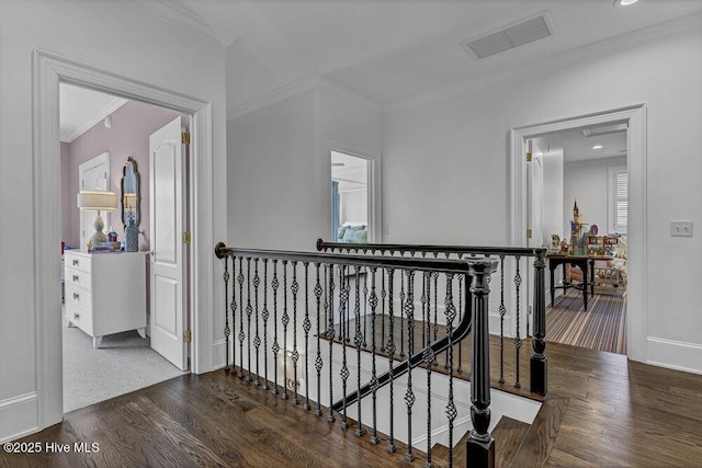 hall with visible vents, ornamental molding, wood finished floors, and an upstairs landing