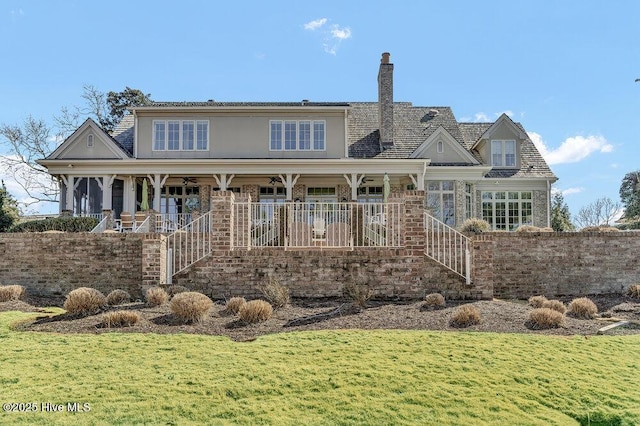 view of front facade featuring covered porch, a chimney, and a front yard