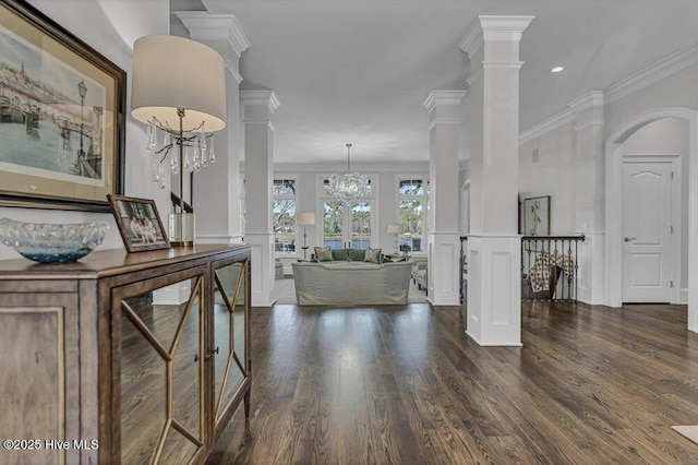 interior space with crown molding, dark wood-type flooring, a decorative wall, and ornate columns