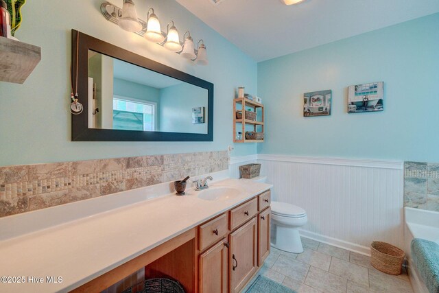 full bath with a wainscoted wall, vanity, and toilet