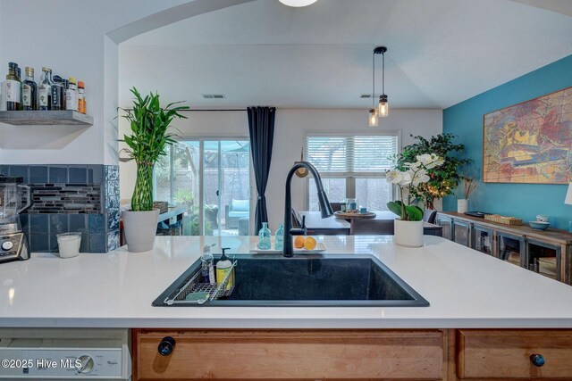 kitchen with light countertops, white appliances, decorative light fixtures, and a sink