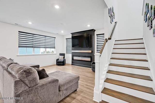 living area featuring recessed lighting, visible vents, light wood-style flooring, baseboards, and stairs