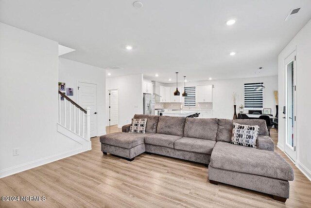 kitchen with stainless steel appliances, light countertops, hanging light fixtures, open floor plan, and white cabinetry