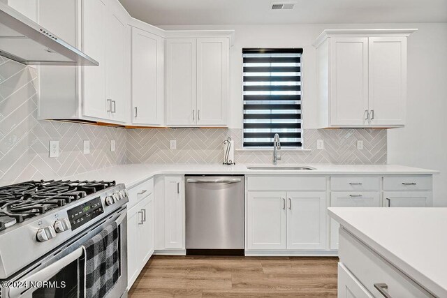 kitchen with appliances with stainless steel finishes, light countertops, white cabinets, and decorative light fixtures