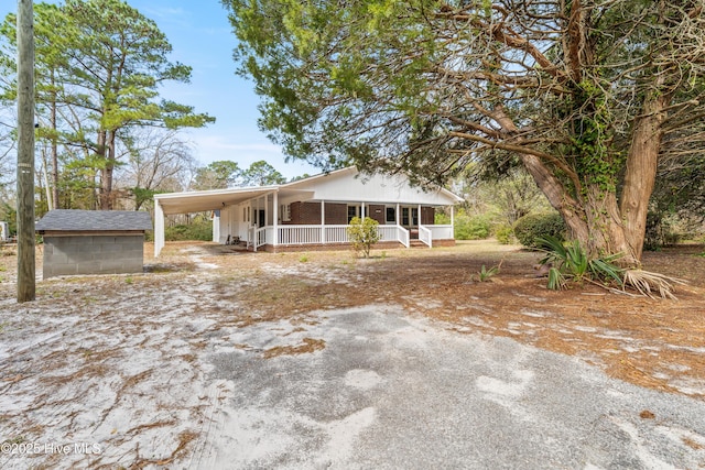 view of front of home with a porch, a carport, and driveway