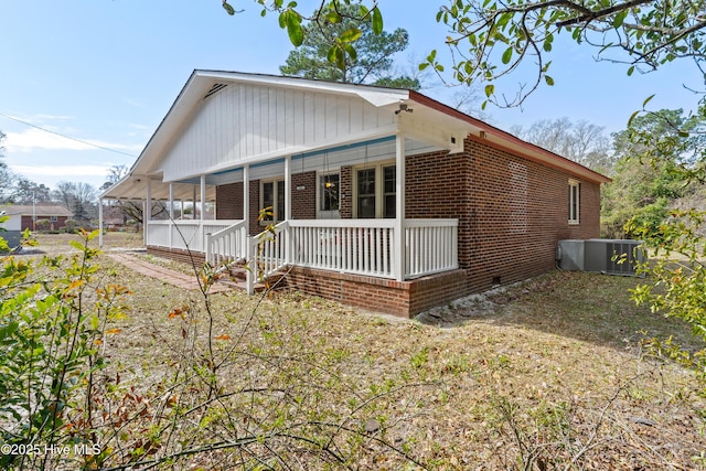 view of front facade with brick siding, crawl space, cooling unit, and a porch