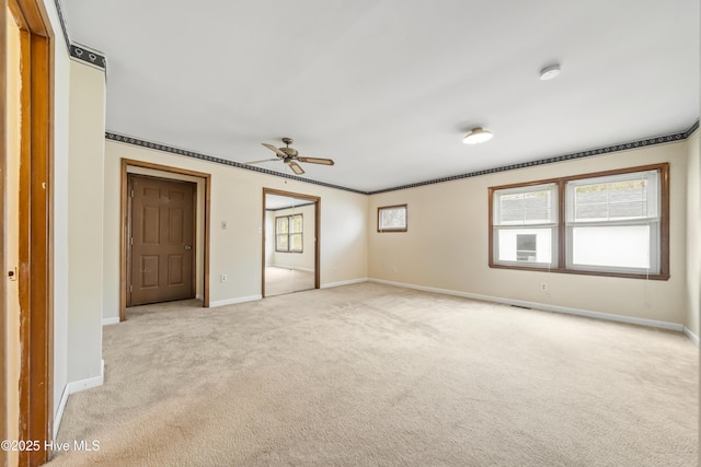 empty room featuring baseboards, light carpet, ceiling fan, and ornamental molding