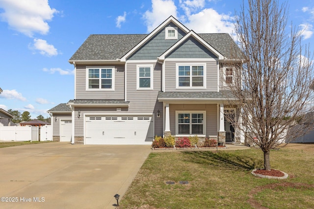 craftsman house with roof with shingles, an attached garage, a front yard, fence, and driveway