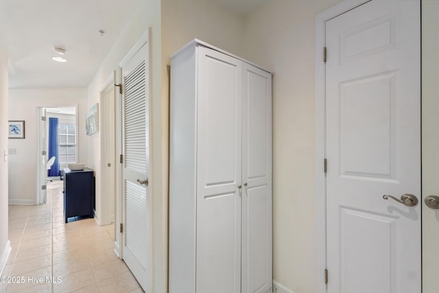 hallway featuring light tile patterned floors and baseboards