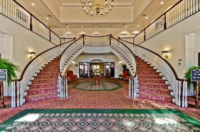 carpeted foyer with stairs, a high ceiling, crown molding, and a notable chandelier