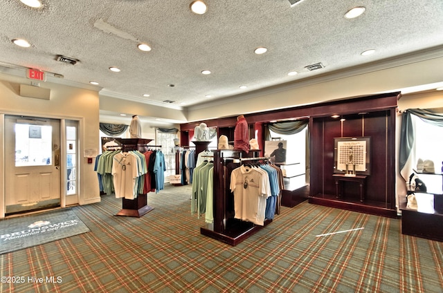 interior space with carpet floors, visible vents, a textured ceiling, and ornamental molding