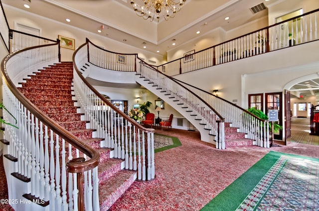 carpeted entryway featuring crown molding, visible vents, stairway, a high ceiling, and an inviting chandelier