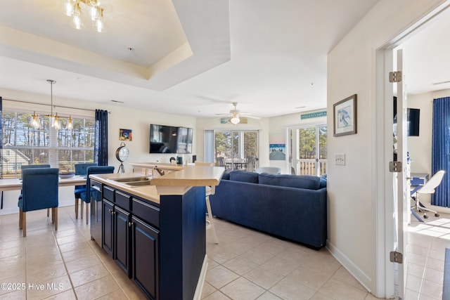 kitchen featuring a center island with sink, light countertops, an inviting chandelier, open floor plan, and dark cabinetry