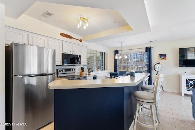 kitchen featuring stainless steel appliances, light countertops, white cabinets, and visible vents