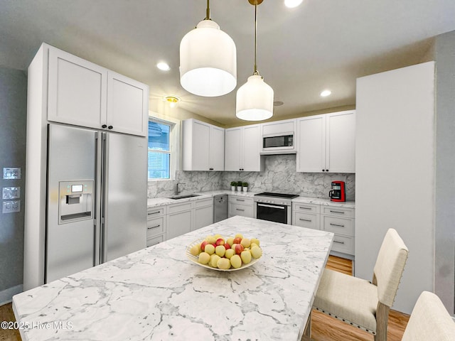 kitchen with stainless steel appliances, hanging light fixtures, white cabinetry, and decorative backsplash