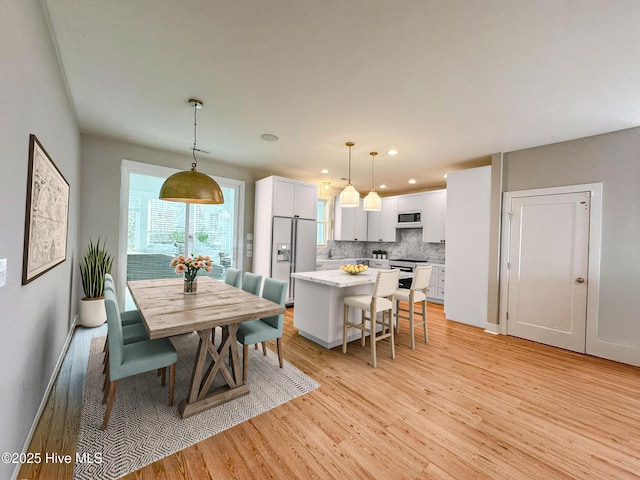 dining space with baseboards, light wood finished floors, and recessed lighting