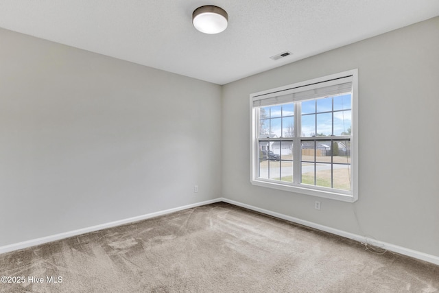 empty room featuring carpet, a textured ceiling, visible vents, and baseboards