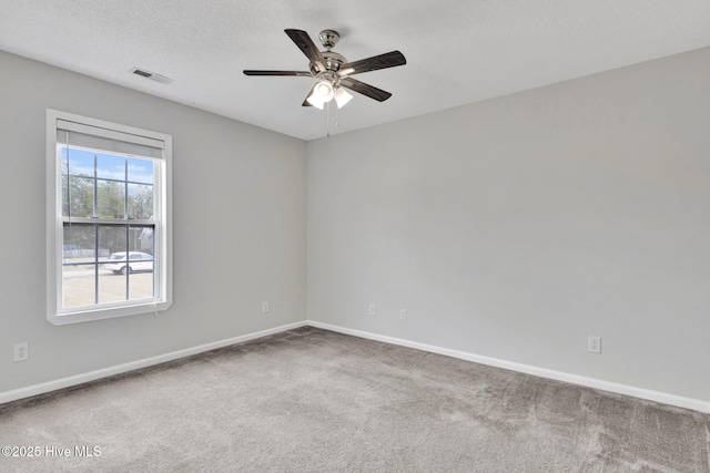 spare room featuring a textured ceiling, visible vents, a ceiling fan, baseboards, and carpet