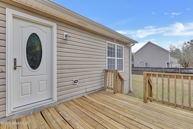 wooden terrace featuring a yard and fence