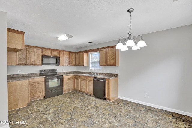 kitchen featuring dark countertops, stone finish floor, a sink, black appliances, and baseboards