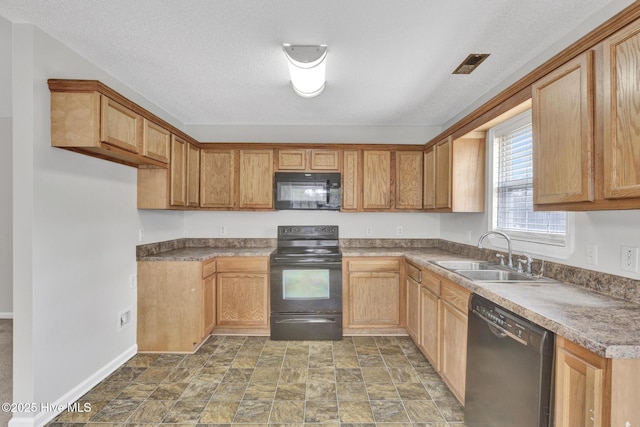 kitchen featuring a textured ceiling, black appliances, a sink, and stone finish flooring