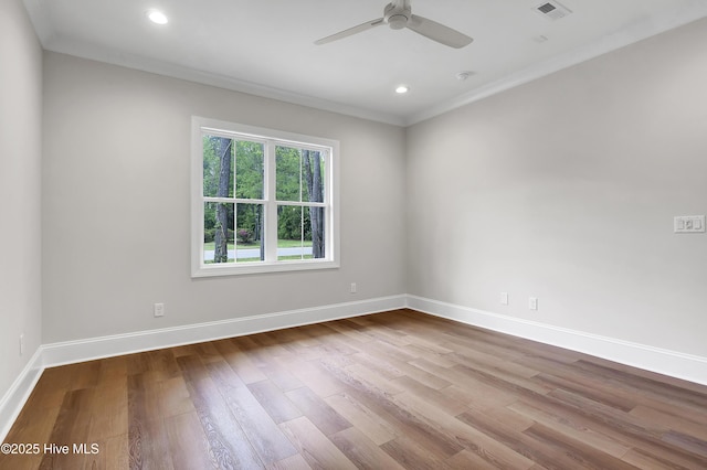 empty room featuring ornamental molding, light wood finished floors, visible vents, and baseboards