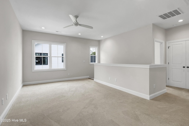 empty room featuring light carpet, recessed lighting, visible vents, and baseboards