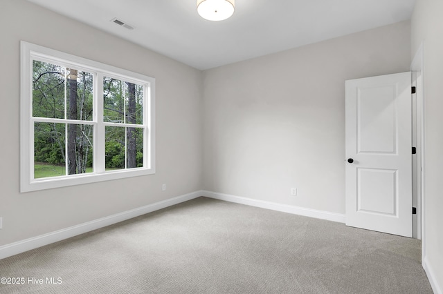 empty room featuring carpet, visible vents, and baseboards