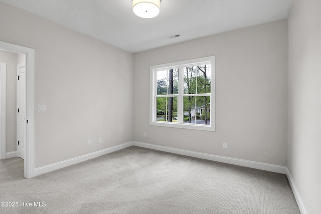 spare room featuring baseboards, visible vents, and light colored carpet